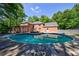 A sparkling pool mirrors the surrounding lush greenery and the home's brick exterior, creating a serene backyard oasis at 1348 Timberland Se Dr, Marietta, GA 30067