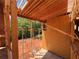 Home under construction with lumber framing and plywood sheathing, offering a glimpse of the surrounding wooded area at 6740 Pannell Rd, Buford, GA 30518