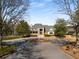 Elegant home featuring a circular driveway with a fountain and meticulously manicured landscaping at 10410 High Falls Cir, Alpharetta, GA 30022