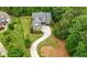 Aerial view of a brick home with a long driveway surrounded by lush green trees at 12980 Overlook Pass, Roswell, GA 30075