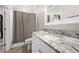 Bathroom featuring a granite countertop vanity, a framed mirror, and a shower-tub with a textured curtain at 12980 Overlook Pass, Roswell, GA 30075