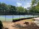 Community tennis court with professional surface, surrounded by green trees and manicured landscaping at 12980 Overlook Pass, Roswell, GA 30075