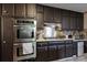 A kitchen featuring dark cabinets, stainless steel appliances, granite counter tops, and tile backsplash, creating a modern cooking space at 1429 Smithson Dr, Lithonia, GA 30058