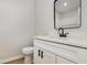Powder room with laminate floors, modern vanity and toilet, and a black framed mirror at 3952 Leisure Se Ct, Conyers, GA 30013