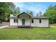 Charming one-story home featuring white siding, a cozy porch, and a beautifully landscaped front yard surrounded by mature trees at 3952 Leisure Se Ct, Conyers, GA 30013