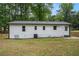 Exterior shot of a white-sided home with a black roof, showcasing the backyard and fencing at 3952 Leisure Se Ct, Conyers, GA 30013