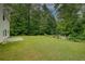 Expansive backyard features a lush lawn, bordered by mature trees, and a charming garden area at 4942 Brown Leaf Dr, Powder Springs, GA 30127