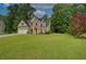 Traditional two-story home with a brick facade, lush green lawn, mature trees, and a two-car garage at 4942 Brown Leaf Dr, Powder Springs, GA 30127