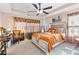 Comfortable bedroom with tray ceilings, ceiling fan, plush carpet, and decorative bed with orange accents at 988 Treymont Way, Lawrenceville, GA 30045