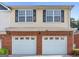Two-story home with a double garage, brick facade, yellow siding and black shuttered windows at 988 Treymont Way, Lawrenceville, GA 30045