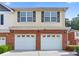 Two-story home with a double garage, brick facade, yellow siding and black shuttered windows at 988 Treymont Way, Lawrenceville, GA 30045