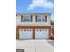 Two-story home with a double garage, brick facade, yellow siding and black shuttered windows at 988 Treymont Way, Lawrenceville, GA 30045