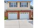Front exterior view of a home showcasing a brick facade and a two-car garage with white doors at 988 Treymont Way, Lawrenceville, GA 30045