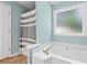 Clean bathroom with a shower and tub combination, window, white cabinets, and plenty of natural light at 130 Lacey Oak Ln, Loganville, GA 30052