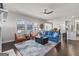 Bright living room with large windows, ceiling fan, blue sofa, and open floor plan, flowing into kitchen at 3560 Summerpoint Xing, Cumming, GA 30028