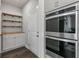 Pantry with floating wood shelves, cabinet storage, stainless steel double ovens, and hardwood floors at 3560 Summerpoint Xing, Cumming, GA 30028