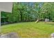 Spacious backyard with a lush green lawn, mature trees, and a playground at 3663 Homewood Trl, Powder Springs, GA 30127