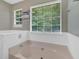 Large soaking tub with tile surround and dual windows providing ample sunlight at 3663 Homewood Trl, Powder Springs, GA 30127
