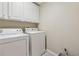 Bright laundry room with a washer and dryer and white storage cabinets at 11715 Dancliff Trce, Alpharetta, GA 30009