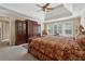 Spacious main bedroom featuring a tray ceiling, large windows, an armoire, and a plush, decorative bedspread at 11715 Dancliff Trce, Alpharetta, GA 30009