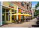 Street view of Fuzziwig's Candy Factory and Goldbergs restaurant with yellow awnings and outdoor tables at 11715 Dancliff Trce, Alpharetta, GA 30009