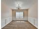 Formal dining room featuring wainscoting, elegant chandelier, and a large window for natural light at 1405 Bramlett Forest Trl, Lawrenceville, GA 30045
