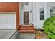 Close-up of front entry with brick steps leading to brown front door, with sidelight window detail at 1405 Bramlett Forest Trl, Lawrenceville, GA 30045