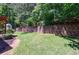 Beautiful backyard featuring a lush lawn, mature trees, and a decorative retaining wall for added privacy at 621 Oakbourne Way, Woodstock, GA 30188