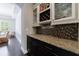 Elegant dining area with a wet bar including granite counters, cabinetry, and a mosaic backsplash at 621 Oakbourne Way, Woodstock, GA 30188
