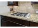 Close-up of a granite countertop and stainless steel gas stovetop with brick backsplash at 621 Oakbourne Way, Woodstock, GA 30188