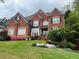 Beautiful two-story brick home with a manicured lawn, colorful flowers, and mature landscaping at 2688 Hidden Falls Ne Dr, Buford, GA 30519