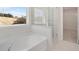 Bright bathroom with tub, glass-enclosed shower, and shelving at 3269 Shirecrest Ln, Dacula, GA 30019