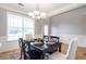 Bright dining room with hardwood floors, wainscoting, modern chandelier, and door leading to other rooms at 4765 Silver Leaf Dr, Cumming, GA 30040