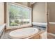 Bright bathroom featuring a luxurious soaking tub with a large window offering serene outdoor views at 65 Wisteria Blvd, Covington, GA 30016