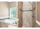 Bathroom showcasing a relaxing soaking tub beneath a window and a beautifully tiled shower stall at 65 Wisteria Blvd, Covington, GA 30016