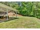 Large grassy backyard featuring a covered patio and mature trees at 209 Wildwood Way, Canton, GA 30114