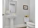 Elegant powder room with pedestal sink, decorative mirror, and stylish fixtures in a neutral color palette at 3264 Andante Ne Dr, Marietta, GA 30062
