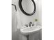 Elegant bathroom features a pedestal sink, dark bronze faucet, and stylish round mirror at 4085 Tritt Homestead Dr, Marietta, GA 30062
