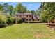Traditional brick home with a lush green lawn, mature trees, and manicured hedges at 5124 Vermack Rd, Dunwoody, GA 30338