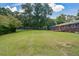 Spacious, green backyard with tall trees, house and wooden patio at 232 Hembredge Dr, Canton, GA 30115