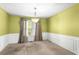 Cozy dining room featuring wainscoting, neutral carpet, and a modern chandelier at 531 Chadborn Ct, Lawrenceville, GA 30045