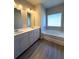 Bathroom boasts double sinks, white cabinets, a luxurious soaking tub, and bright vanity lighting at 5726 Silver Lake Dr, Mableton, GA 30126