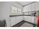 Functional laundry room with white cabinets, dark countertops, stainless steel sink, and red washer at 4015 Wieuca Ne Rd, Atlanta, GA 30342