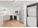 Modern kitchen with stainless steel appliances, white cabinets, a stacked washer/dryer, and wood-look flooring, maximizing space at 525 Parkway Ne Dr # 110, Atlanta, GA 30354