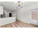 Open-concept space with modern lighting and wood-look flooring, leading to a kitchen area with white cabinets and stainless appliances at 525 Parkway Ne Dr # 110, Atlanta, GA 30354