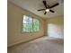 Bright carpeted bedroom featuring a ceiling fan and a window with views of mature trees at 5307 Red Rock Trce, Powder Springs, GA 30127