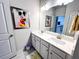 Bright bathroom featuring double sinks, a large mirror, and grey tile flooring at 7860 Bristol Valley Dr, Cumming, GA 30028