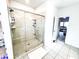 Bright bathroom featuring a glass-enclosed shower with tile surround and white tiled floors at 7860 Bristol Valley Dr, Cumming, GA 30028