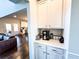 Coffee bar area with white cabinets and a view into the adjacent living and dining spaces at 7860 Bristol Valley Dr, Cumming, GA 30028