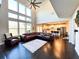 Open-concept living room featuring soaring ceilings, a leather sectional, and a view of the modern kitchen at 7860 Bristol Valley Dr, Cumming, GA 30028